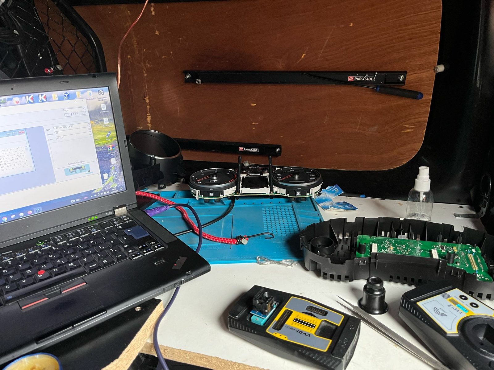 Audi TT instrument cluster opened on the workshop bench next to an EEPROM programmer and a laptop running the immobiliser read